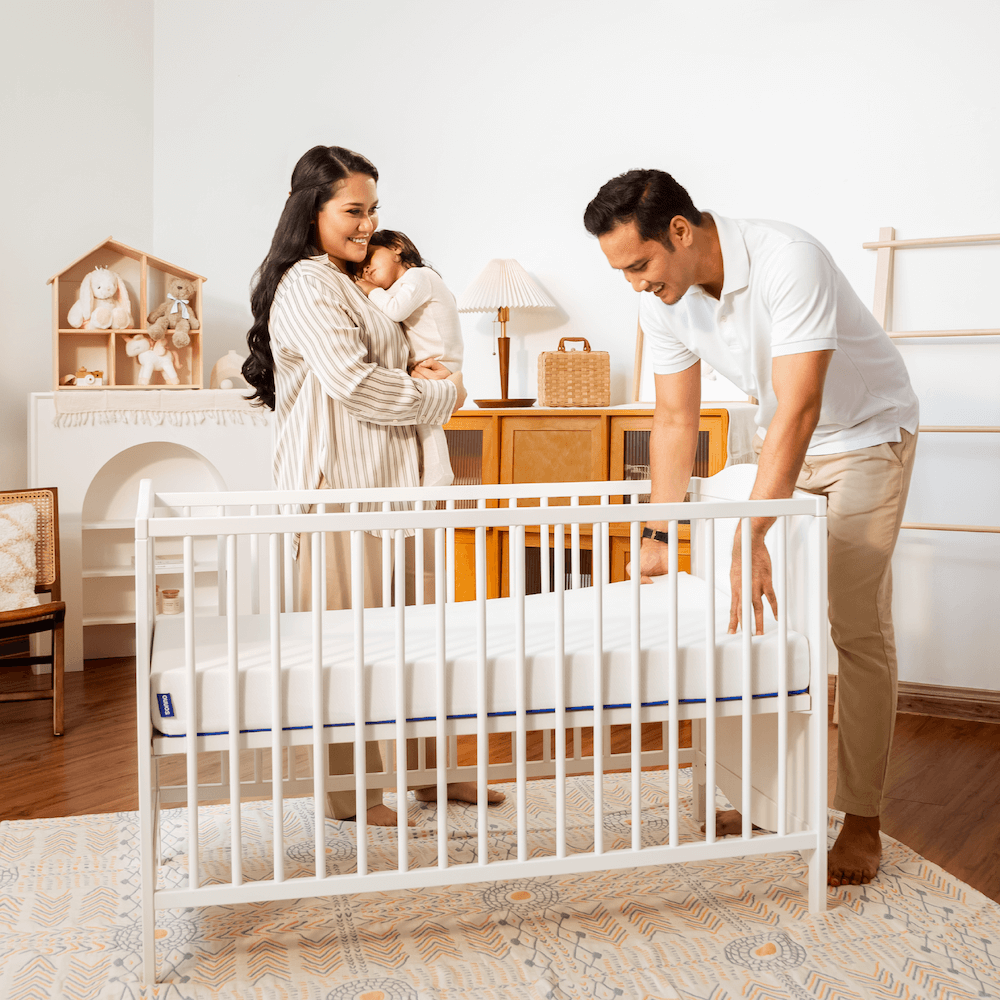 Parents with their baby using Sonno baby mattress in a crib, highlighting comfort and safety for newborns in Malaysia.