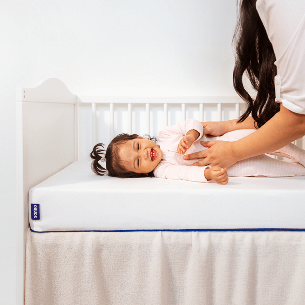 Happy baby resting on Sonno hypoallergenic baby mattress, designed for optimal sleep support in cribs and cots.