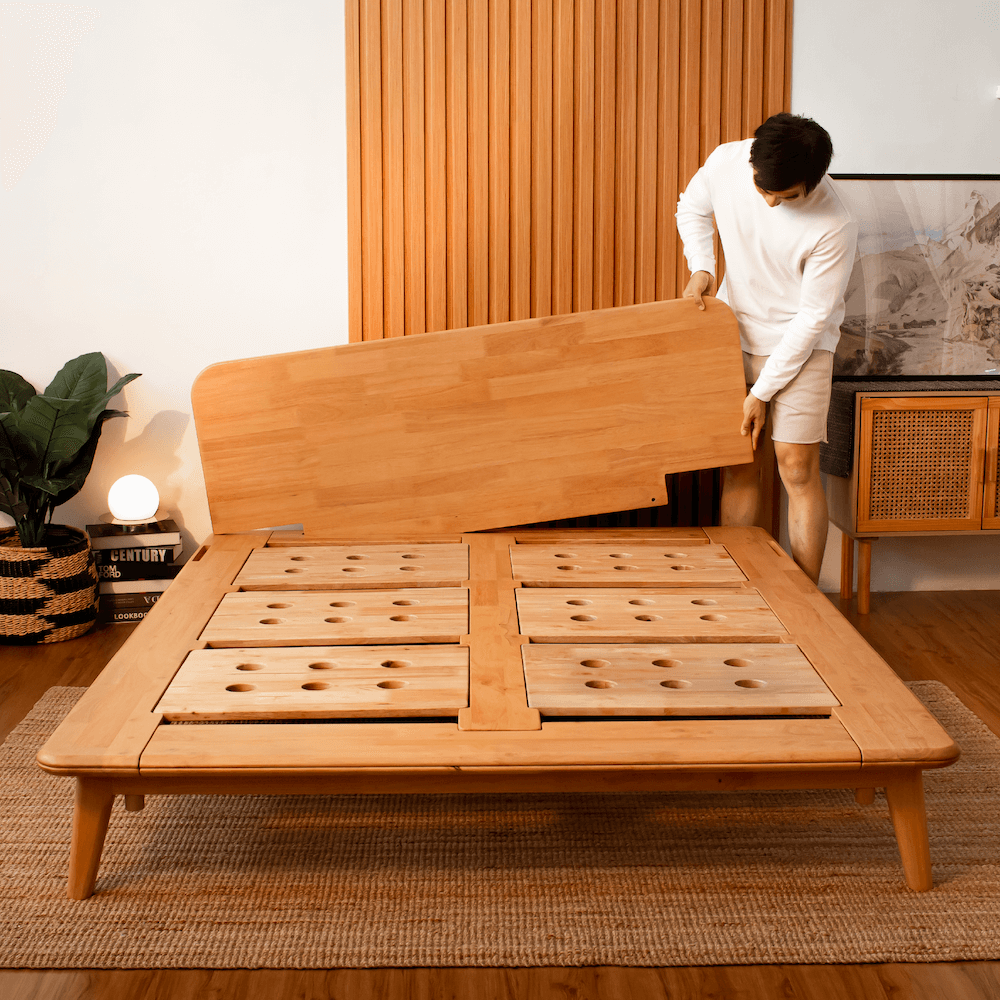 Man assembling Sonno wooden bed frame with no tools required, showcasing simple and efficient bed setup.