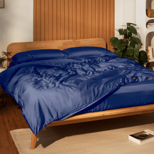 Sonno Tencel bed sheets on wooden bed frame, showcasing luxurious, eco-friendly fabric in a cozy bedroom setting.