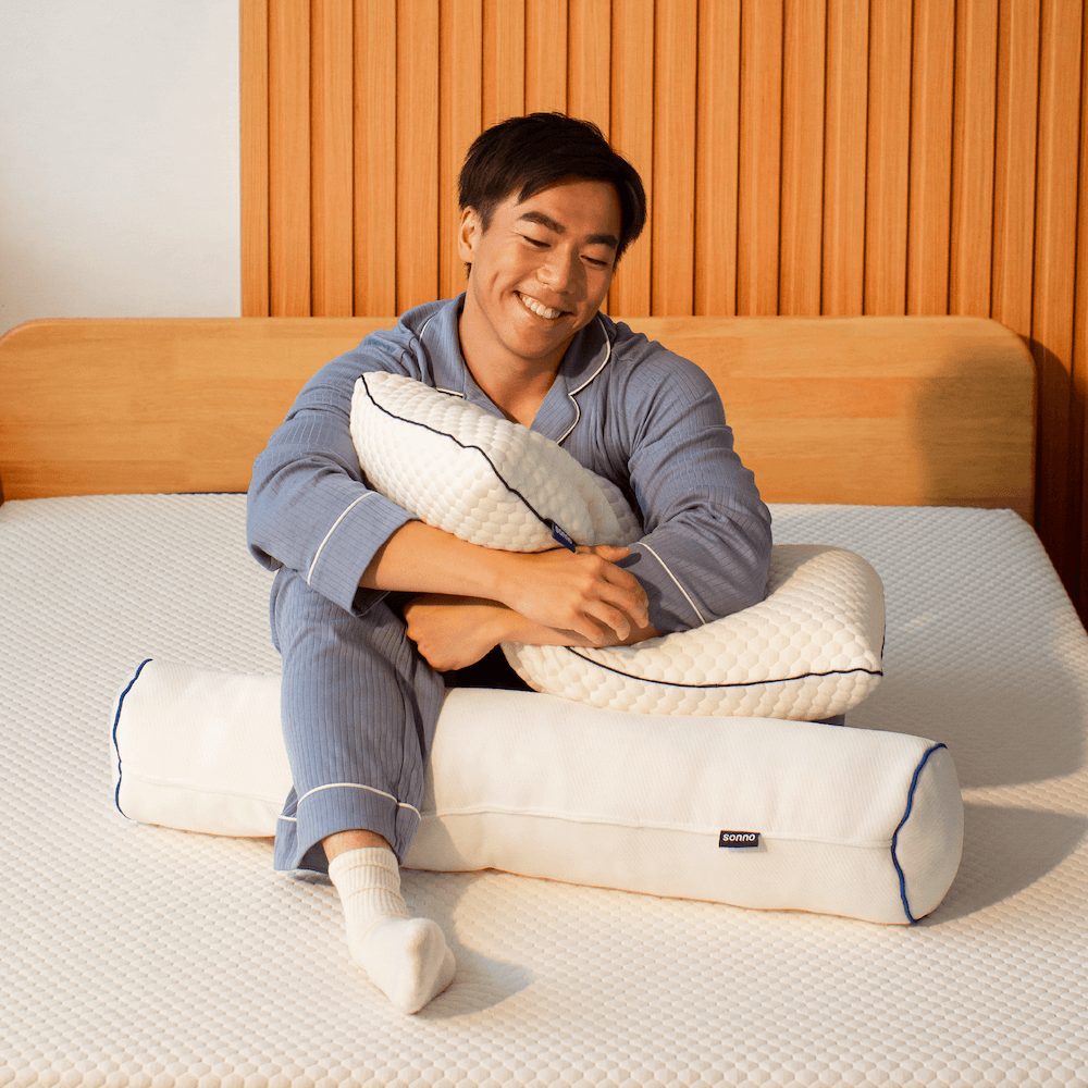 Man enjoying the comfort of the Sonno bolster pillow on a Sonno mattress, designed for optimal support and relaxation.