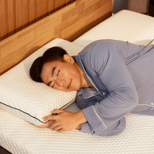 Man sleeping comfortably on Sonno memory foam pillow for neck and spine support.