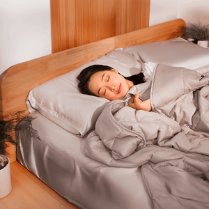 Woman sleeping peacefully under Sonno weighted blanket, designed to evenly distribute weight and improve sleep quality.